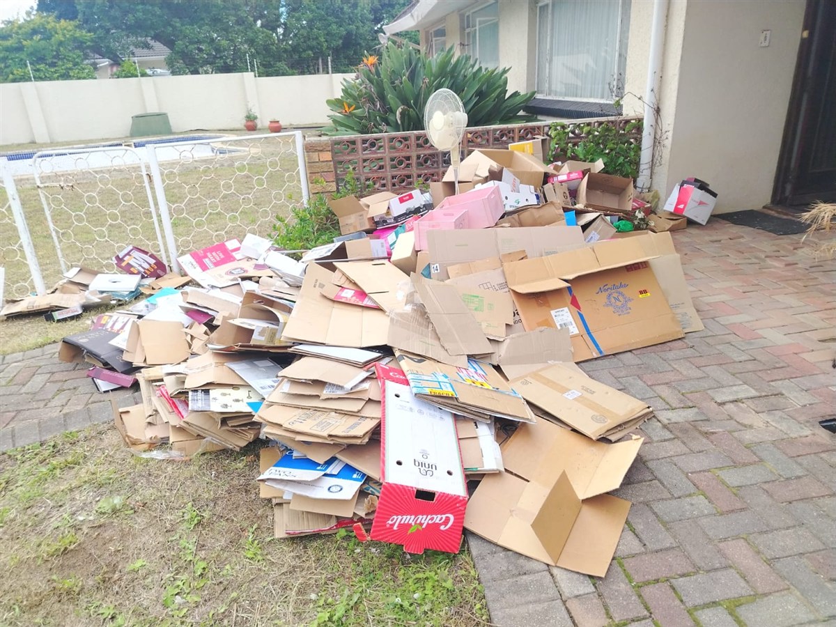 Flattened cardboard and packaging cleared from a home and stacked outside, ready to be taken away