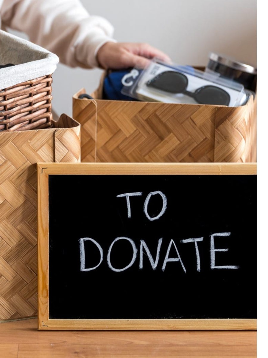 A basket of goods sorted to donate beside a chalkboard reading TO DONATE