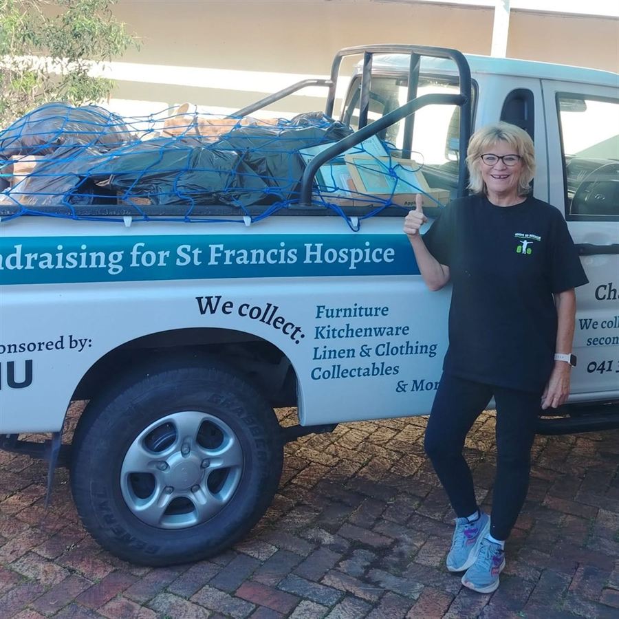 Robyn standing beside a charity collection bakkie loaded with bags and boxes under a cargo net