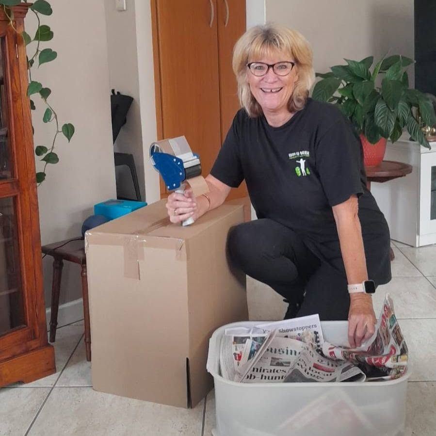 Robyn wrapping belongings in paper and packing them away by hand
