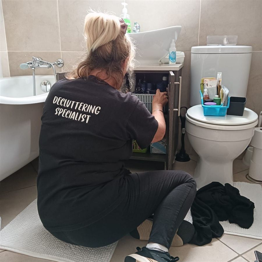 Robyn sorting out the cupboard under a client's bathroom basin